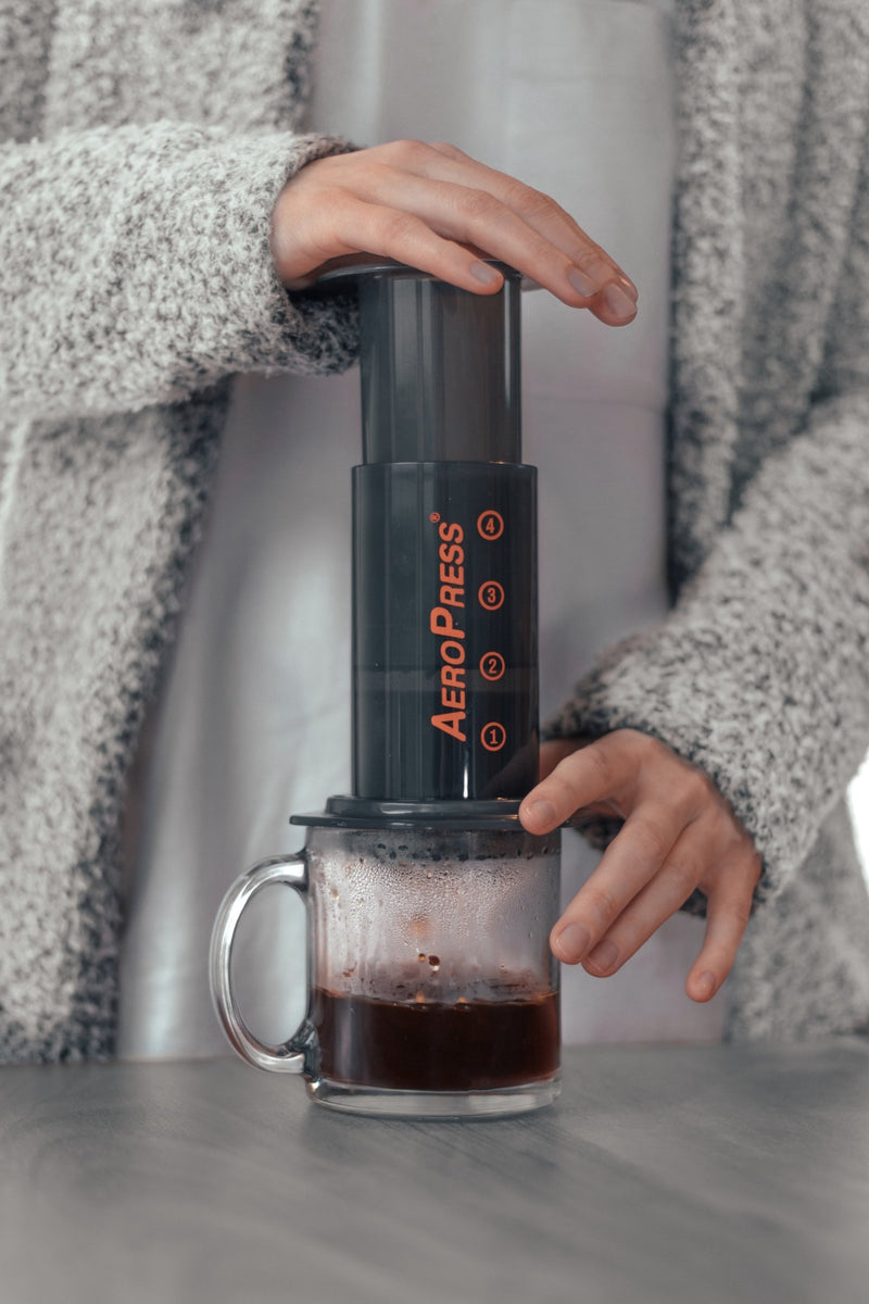 http://rockwoodcoffeeco.com/cdn/shop/products/PersoninsweaterpressingAeroPress_byNikkiBiggerandBenWaugh_1200x1200.jpg?v=1675455319